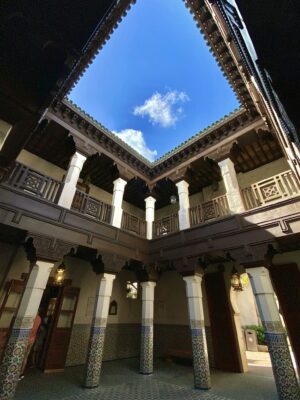 Old house with colonnade under bright blue sky with clouds