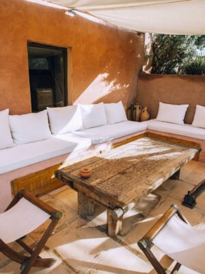 Roofed terrace with furniture near green trees in sunlight