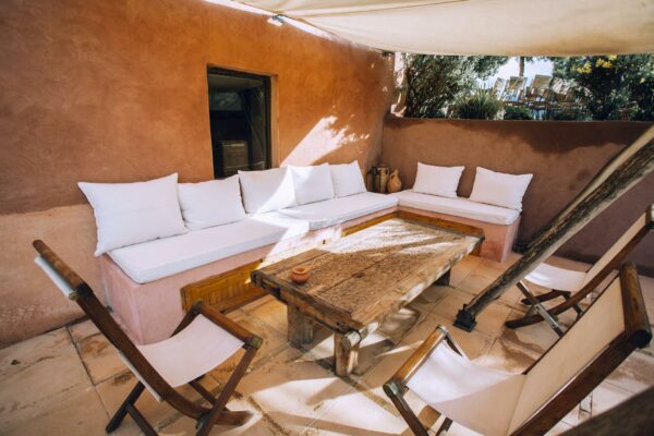 Roofed terrace with furniture near green trees in sunlight