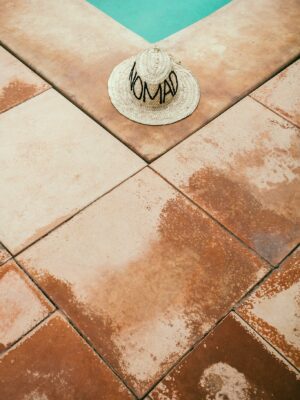 Straw hat on rough tiled poolside in summer