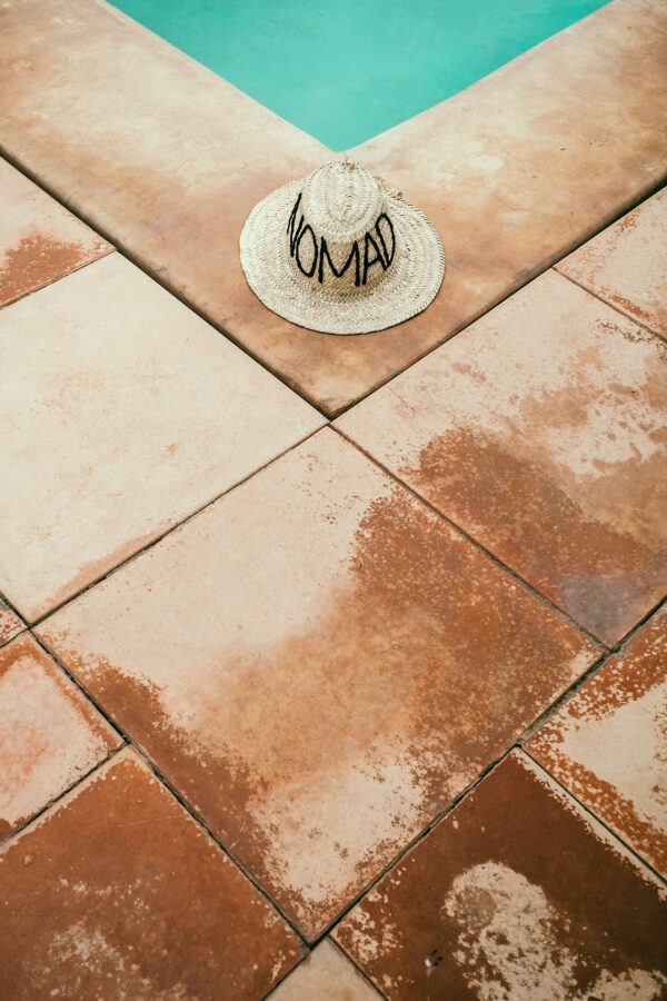 Straw hat on rough tiled poolside in summer